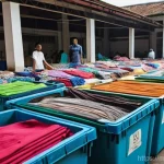 재생 섬유 활용을 위한 협력 네트워크 구축 - **Textile Collection and Community Action in Malaysia:**
A vibrant, wide-angle shot of a bustlin...